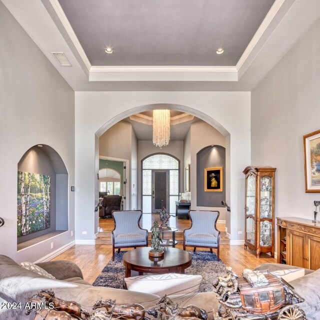 7101 E Berneil Ln, Paradise Valley, AZ 85253 - living room featuring a tray ceiling, light wood-style floors, arched walkways, baseboards, and ornamental molding