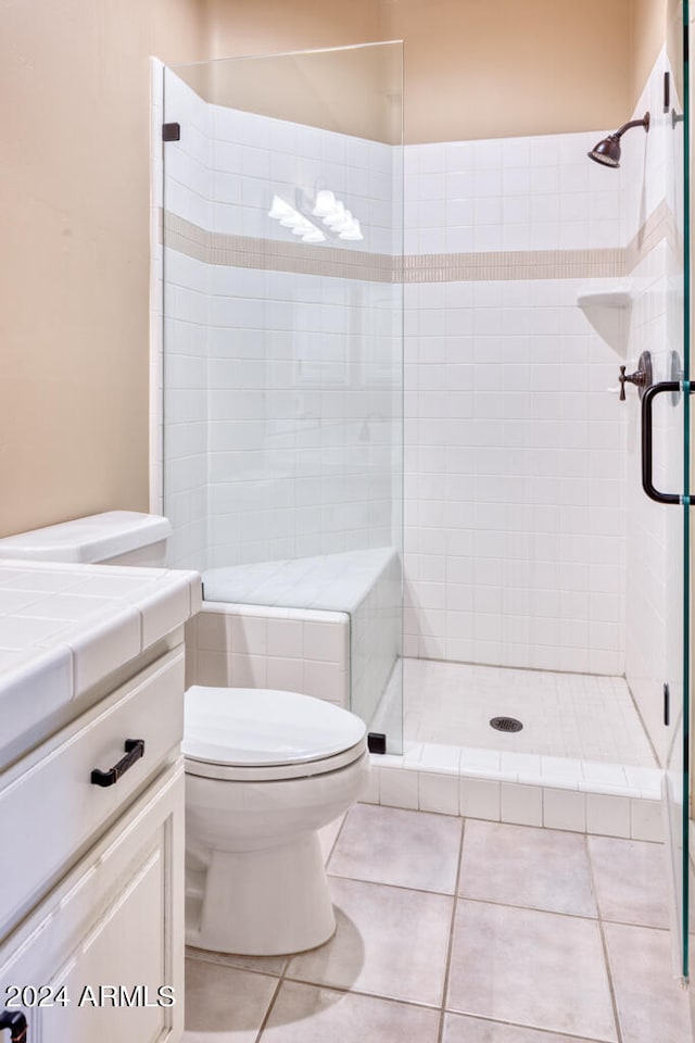 bathroom with vanity, tile patterned flooring, a shower with shower door, and toilet