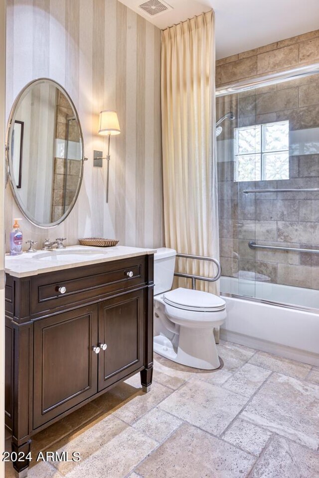 7101 E Berneil Ln, Paradise Valley, AZ 85253 - bathroom featuring stone tile flooring, toilet, vanity, and combined bath / shower with glass door