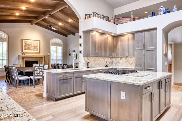 kitchen with light stone counters, a kitchen island, high vaulted ceiling, wooden ceiling, and light hardwood / wood-style floors