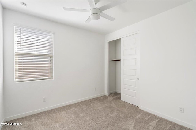 unfurnished bedroom featuring a closet, light colored carpet, and ceiling fan