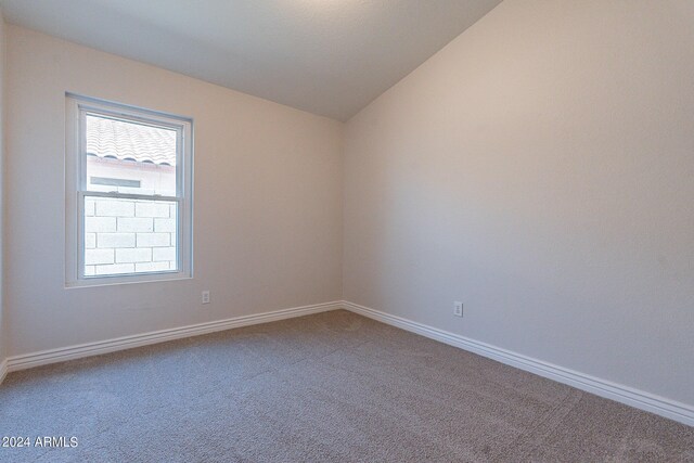 carpeted spare room featuring vaulted ceiling