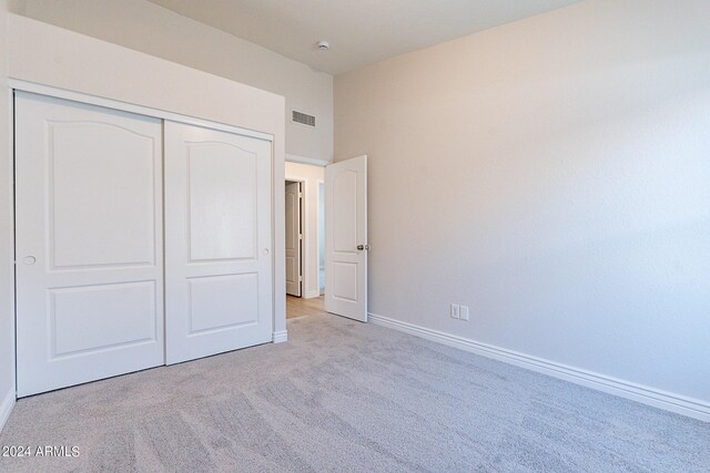 unfurnished bedroom with light carpet and a closet