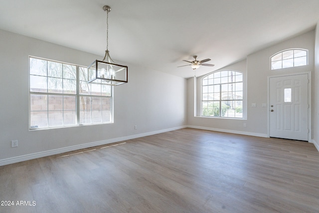 foyer with light wood-type flooring, ceiling fan with notable chandelier, and lofted ceiling