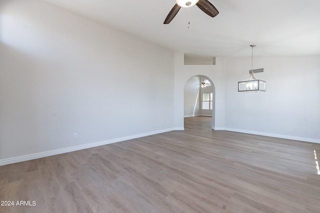 spare room with ceiling fan with notable chandelier, lofted ceiling, and wood-type flooring