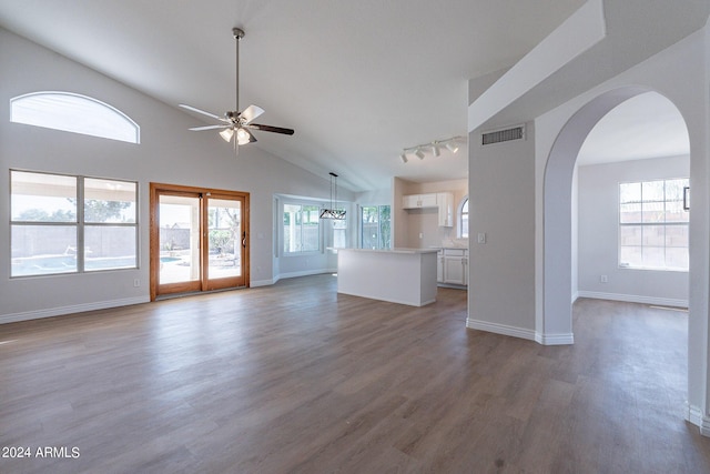 unfurnished living room featuring arched walkways, dark wood-style flooring, visible vents, ceiling fan, and baseboards