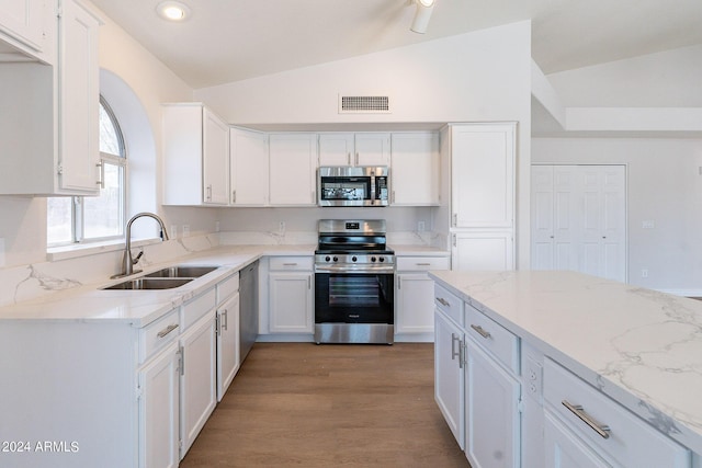 kitchen featuring visible vents, lofted ceiling, appliances with stainless steel finishes, white cabinetry, and a sink