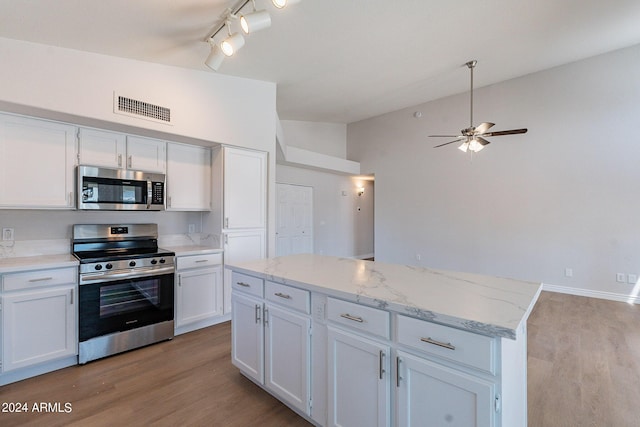 kitchen with visible vents, appliances with stainless steel finishes, white cabinets, vaulted ceiling, and a kitchen island