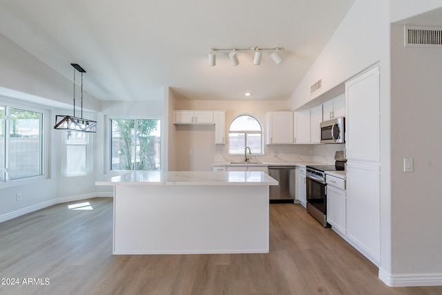 kitchen featuring white cabinets, lofted ceiling, decorative light fixtures, a center island, and stainless steel appliances