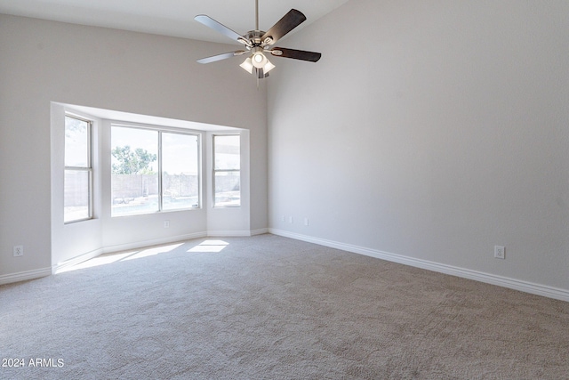 spare room with baseboards, a high ceiling, a ceiling fan, and light colored carpet