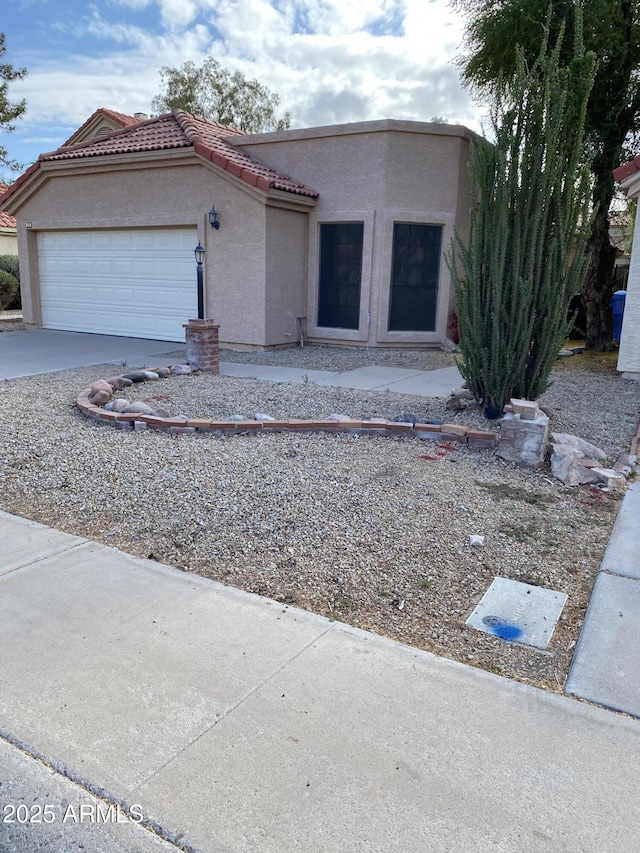 view of front of house featuring an attached garage, a tile roof, concrete driveway, and stucco siding