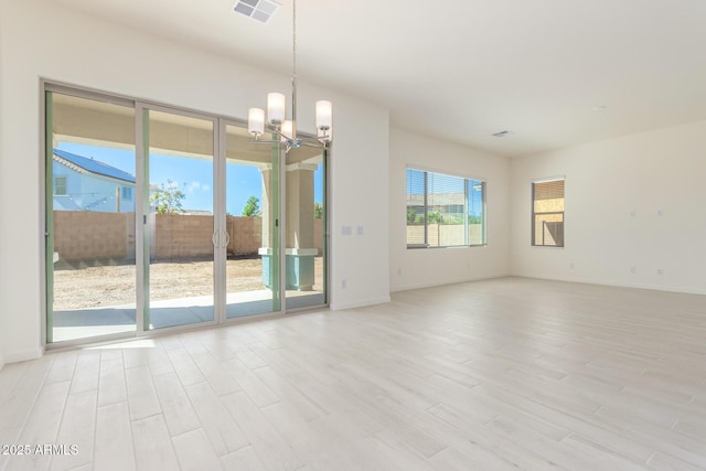 spare room with an inviting chandelier and light wood-type flooring