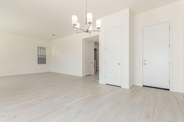 spare room featuring an inviting chandelier and light wood-type flooring