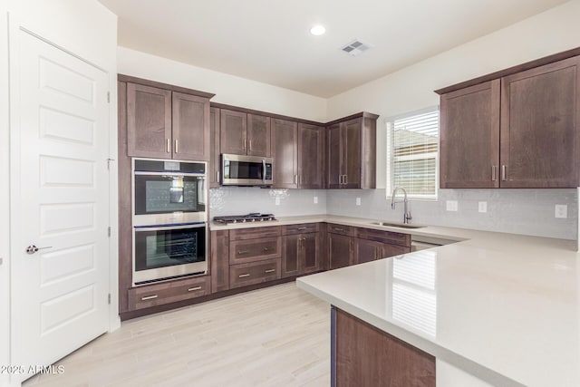 kitchen with sink, backsplash, dark brown cabinets, and stainless steel appliances