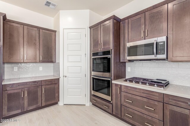 kitchen with decorative backsplash, dark brown cabinets, stainless steel appliances, and light wood-type flooring