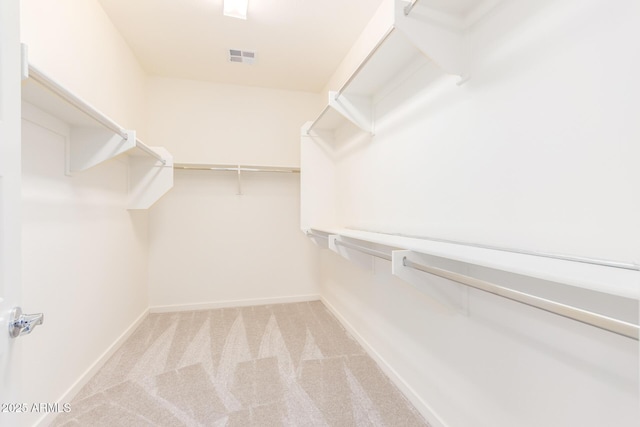 walk in closet featuring light colored carpet