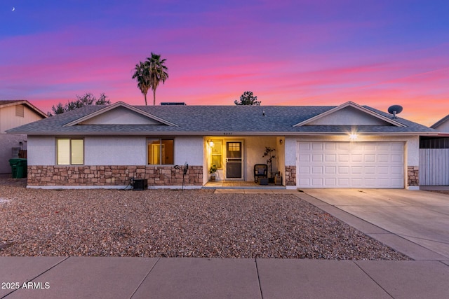 ranch-style home featuring a garage, stone siding, driveway, and stucco siding