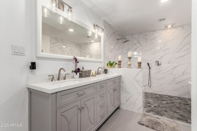 full bathroom featuring double vanity, visible vents, a sink, and a walk in shower