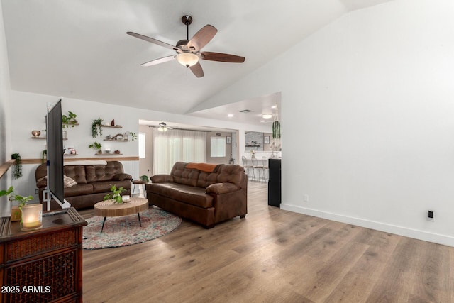 living area featuring high vaulted ceiling, wood finished floors, a ceiling fan, and baseboards