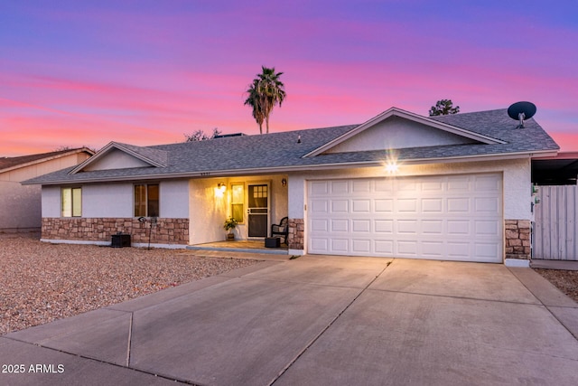 single story home featuring an attached garage, stone siding, concrete driveway, roof with shingles, and stucco siding