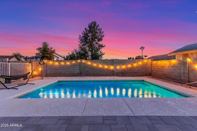 pool at dusk with a patio area, a fenced backyard, and a fenced in pool