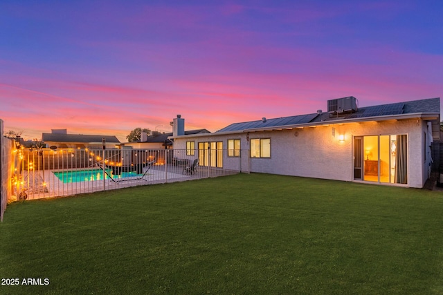 back of house at dusk with central AC, a lawn, a patio area, and stucco siding