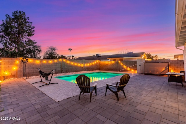 pool at dusk featuring a fenced backyard, a fenced in pool, and a patio