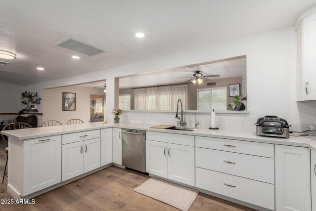 kitchen with a peninsula, a sink, visible vents, white cabinets, and stainless steel dishwasher