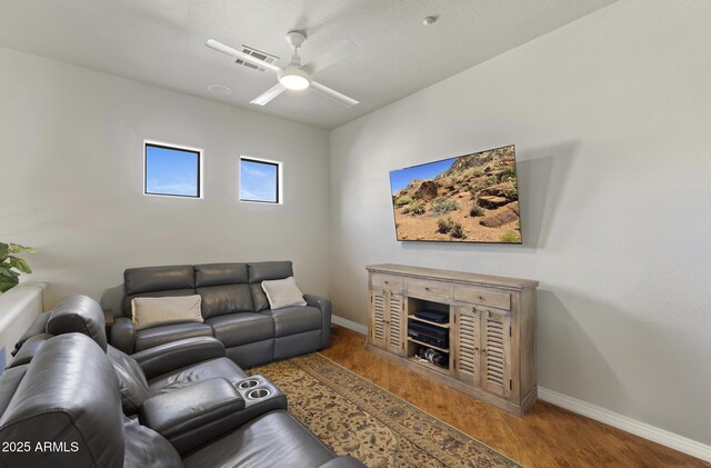 living room with a ceiling fan, visible vents, baseboards, and wood finished floors