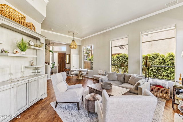 living area with wood finished floors, visible vents, and crown molding