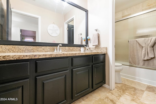 full bathroom with bath / shower combo with glass door, vanity, and toilet