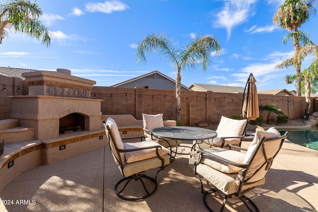 view of patio featuring an outdoor fireplace and a fenced in pool