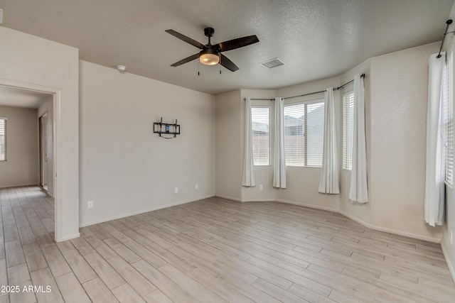 spare room with ceiling fan, light hardwood / wood-style floors, and a textured ceiling