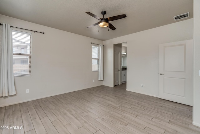 spare room with ceiling fan, a textured ceiling, and light wood-type flooring