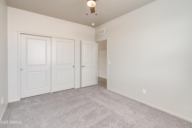 unfurnished bedroom featuring ceiling fan, light colored carpet, and a closet