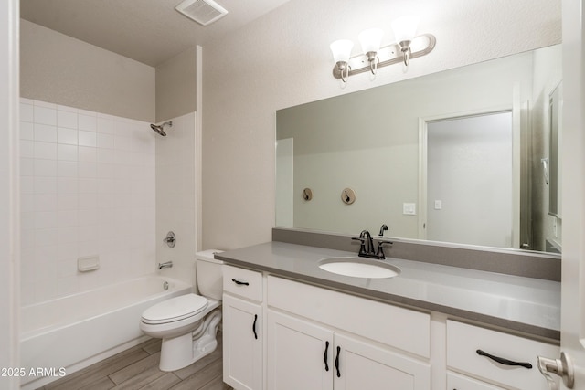 full bathroom featuring tiled shower / bath combo, vanity, hardwood / wood-style flooring, and toilet