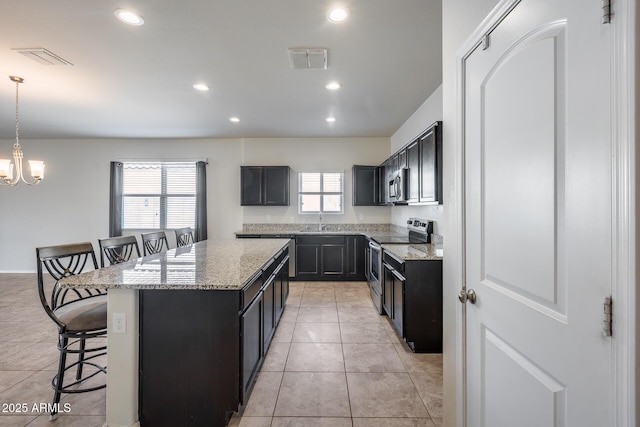 kitchen with a breakfast bar area, hanging light fixtures, a center island, light tile patterned floors, and stainless steel appliances