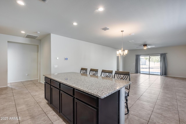 kitchen featuring light stone counters, a kitchen bar, a center island, and light tile patterned floors