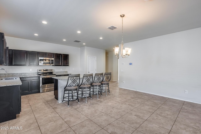 kitchen featuring sink, light stone counters, a kitchen island, pendant lighting, and stainless steel appliances