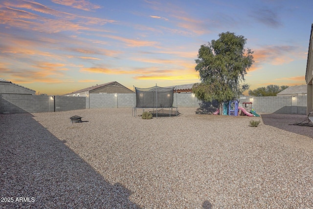 yard at dusk with a playground and a trampoline