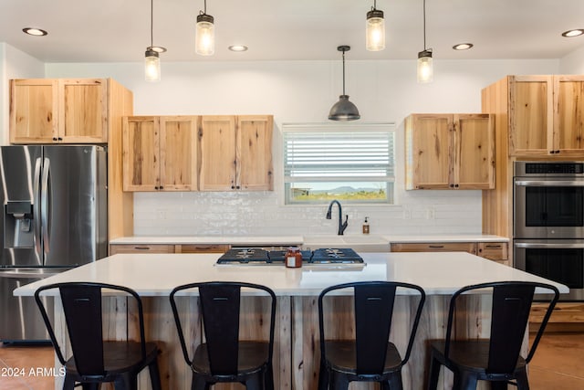 kitchen featuring appliances with stainless steel finishes, decorative light fixtures, a breakfast bar area, and a center island