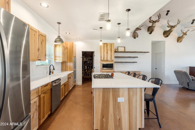 kitchen with pendant lighting, appliances with stainless steel finishes, sink, and a breakfast bar