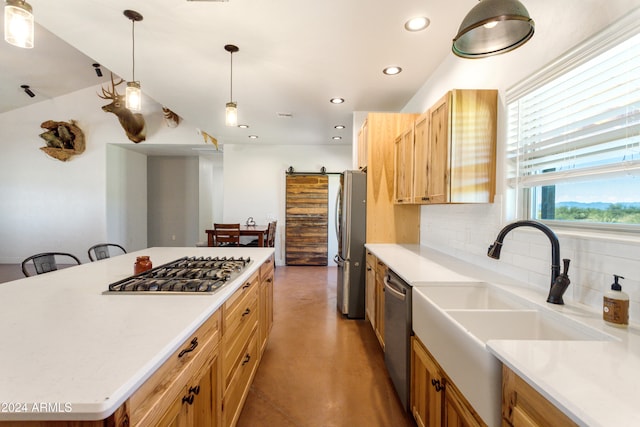 kitchen featuring stainless steel appliances, sink, tasteful backsplash, hanging light fixtures, and a barn door