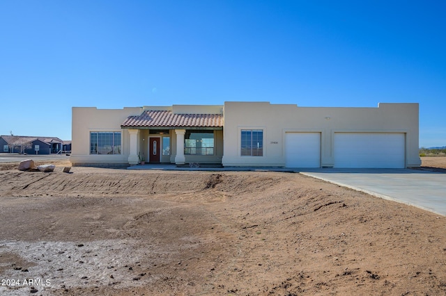 southwest-style home featuring a garage, stucco siding, and driveway