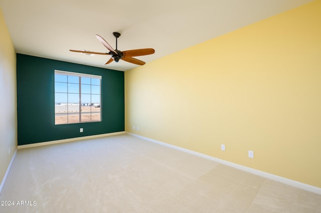 carpeted spare room featuring baseboards and ceiling fan