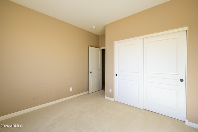 unfurnished bedroom with a closet and light colored carpet