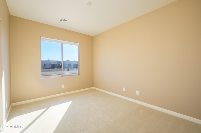 spare room featuring baseboards, light carpet, and visible vents