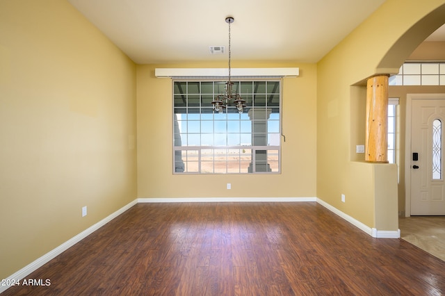 foyer entrance featuring dark hardwood / wood-style floors, a chandelier, plenty of natural light, and decorative columns