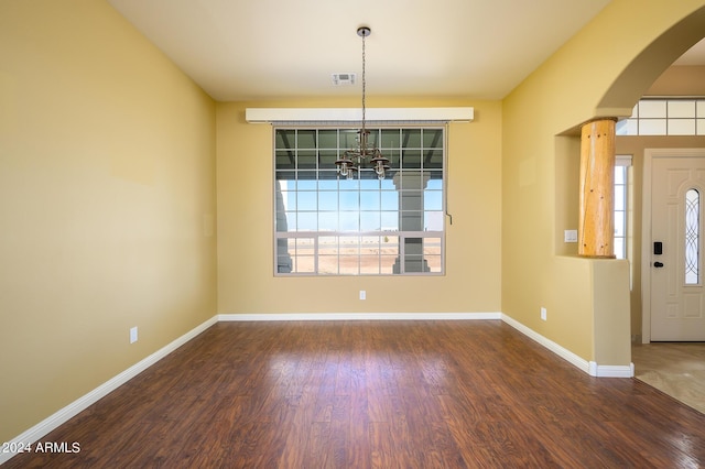 foyer with arched walkways, a notable chandelier, visible vents, and wood finished floors