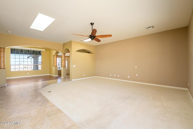 empty room with visible vents, arched walkways, baseboards, and a ceiling fan